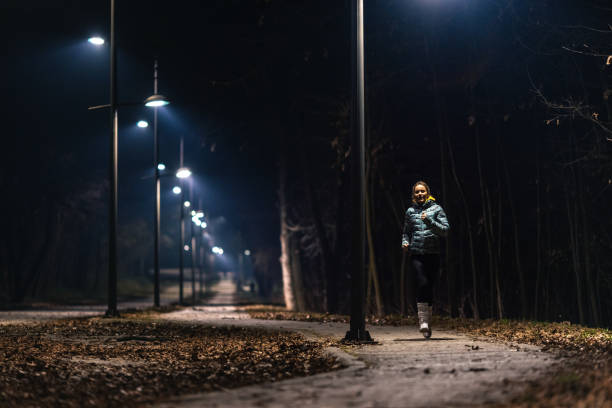 istock Young woman jogging in park at night 1980045420