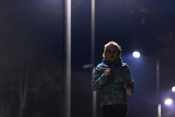 istock Young woman jogging in park at night 1980045615