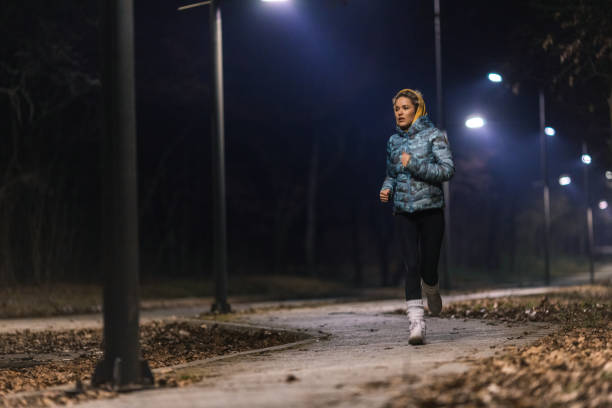 istock Young woman jogging in park at night 1980045966