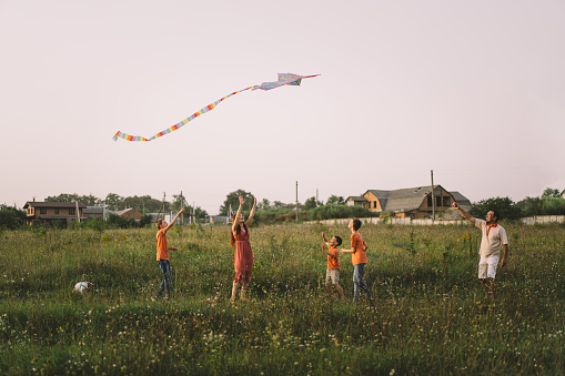 happy kid boy running with a kite at sunset outdoors