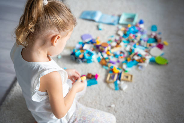 Little girl play with constructor toy on floor in home, educational game, spending leisure activities time concept. Focus on child. High quality photo