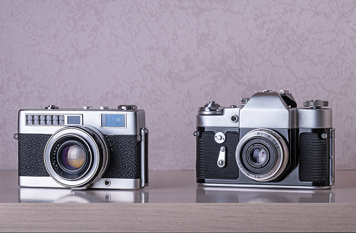 Vintage SLR cameras on wooden shelf.