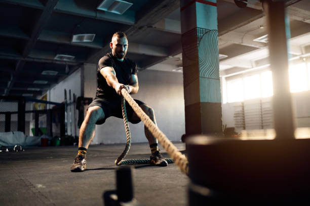 istock In the gym, strong male athlete pulling weights with rope 1980087303