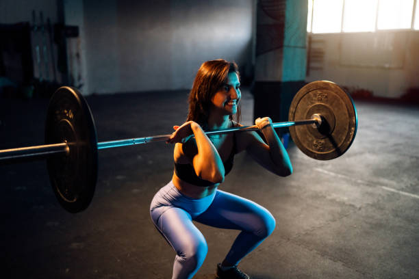istock Active young Caucasian woman, doing squats with barbell 1980092410