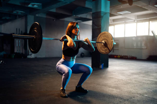 istock Active young Caucasian woman, doing squats with barbell 1980092422