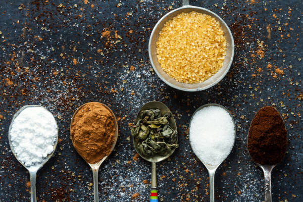 istock Spoons with icing sugar, green tea, coffee and cocoa on black background sprinkled with sugar, coffee, cocoa powder. 1980095746