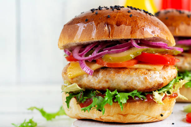 istock Chicken hamburger. Sandwich with chicken burger, tomatoes, cheese, pickled cucumber and lettuce. Cheeseburger. 1980099078