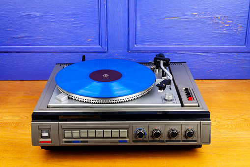 Vintage turntable vinyl record player with blue vinyl on a table