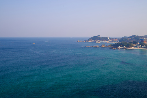 Samcheok City, South Korea - December 28, 2023: An aerial shot captures the expansive East Sea's vast blue, with Jangho Port and Yonghwa Beach visible on the picture's right, showcasing the natural and developed harmony along the coastline.