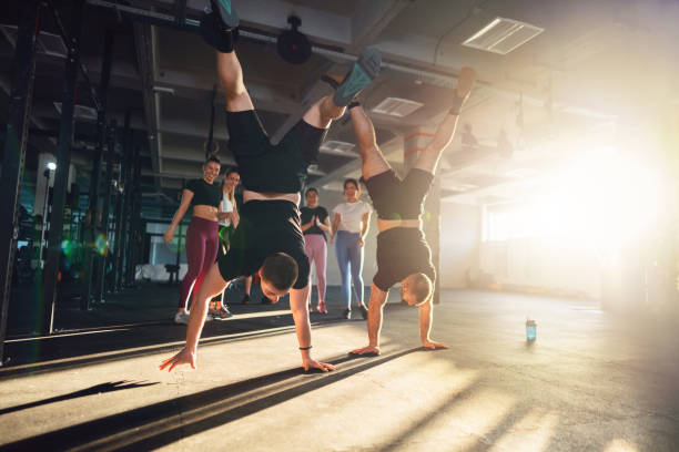 istock Men walking on hands, while rest of the group cheers them, during an group workout at the gym 1980102938
