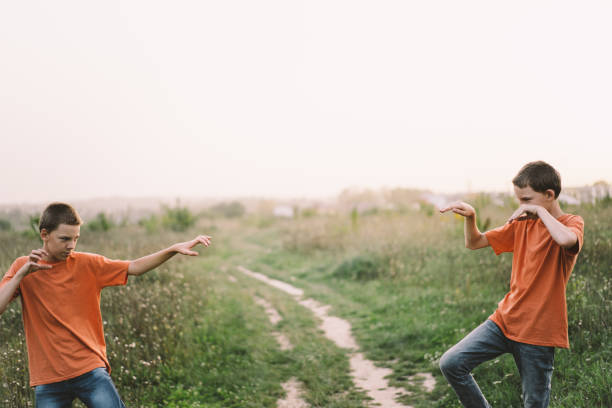 Funny twin brother boys in orange t-shirt playing outdoors on field at sunset. Happy children, lifestyle.