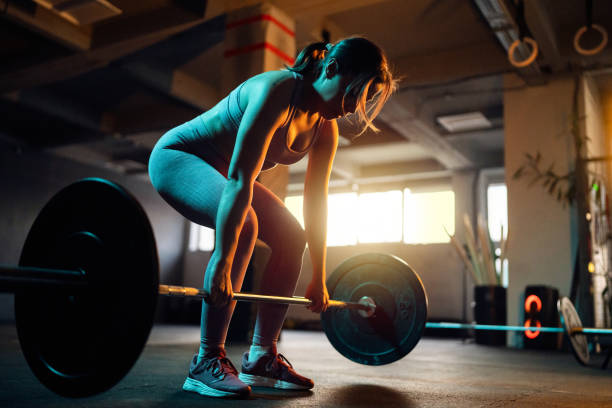 istock Female athlete doing squats with barbell in the gym 1980109551
