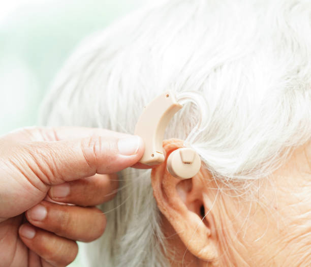 istock Doctor install hearing aid on senior patient ear to reduce hearing loss problem. 1980110109