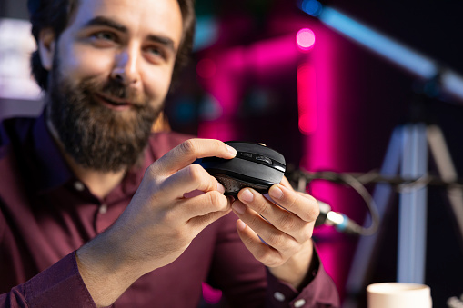 Close up of joyful influencer endorsing wireless mouse from sponsor, showing functionalities. Excited internet star promotes computer peripheral from partnering brand to followers on social media
