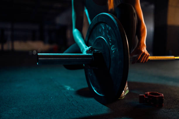 istock Woman adjusting weights on a barbell, during workout in the gym 1980125437