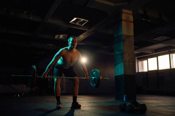 istock Young man exercise with barbell and weights in the gym 1980129922