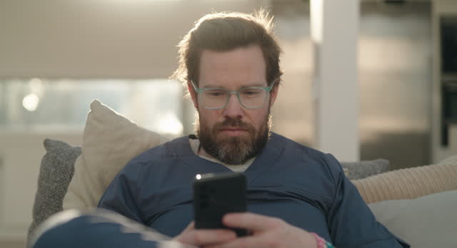 Man sitting in the living room in the morning, using his smartphone