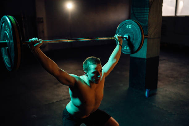 istock Young man doing squats with barbell and weights in the gym 1980130891