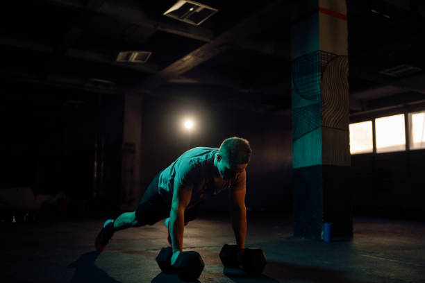 istock Young man exercise with dumbbell in the gym, while doing push-ups 1980134616