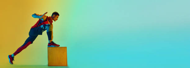 istock Athletic man training, doing exercises with wooden box against gradient blue yellow background in neon light. Banner 1980137499
