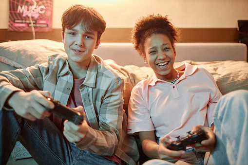 Portrait of two teenage friends playing videogames together with console and having fun