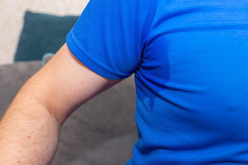 Man With Hyperhidrosis Sweating Very Badly Under Armpit.Man sweating excessively smelling bad at home.Closeup.