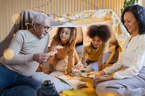 бабушки, дедушки и внуки наслаждаются моментом в самодельном форте - grandparent family reading inside of стоковые фото и изображения