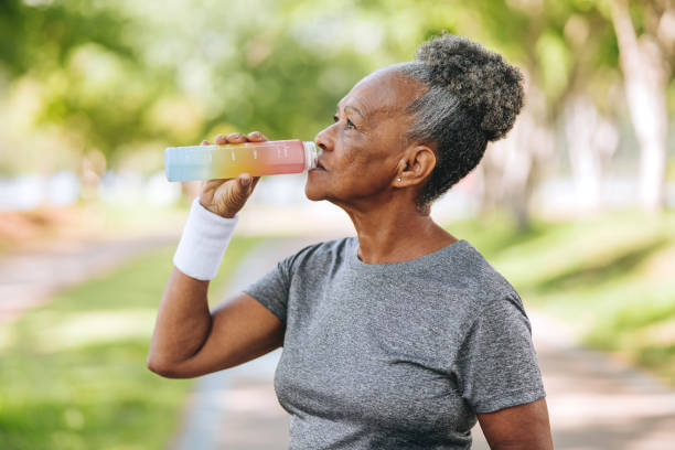 istock Senior woman drinking water in public park 1980166766