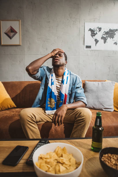 istock Young man watching soccer game at home 1980199475