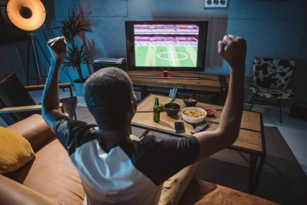 istock Young man watching soccer game at home 1980207111