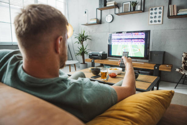 istock Young man watching soccer game at home 1980209304