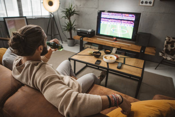 istock Young man watching soccer game at home 1980218914