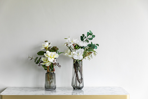 beautiful white flower in vase on background old wall