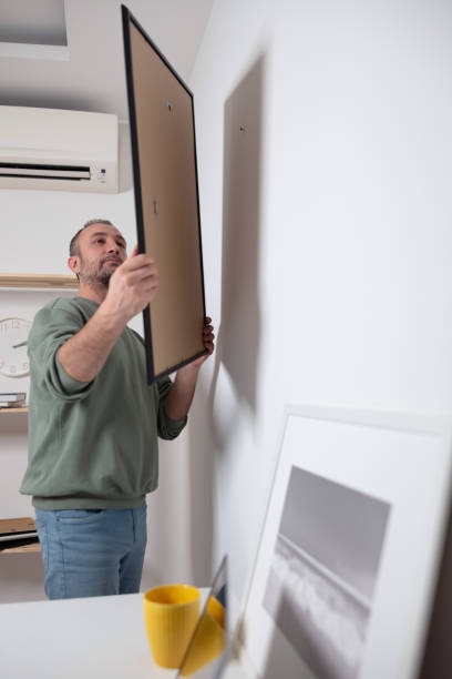 istock Man hanging pictures on the wall. 1980224826