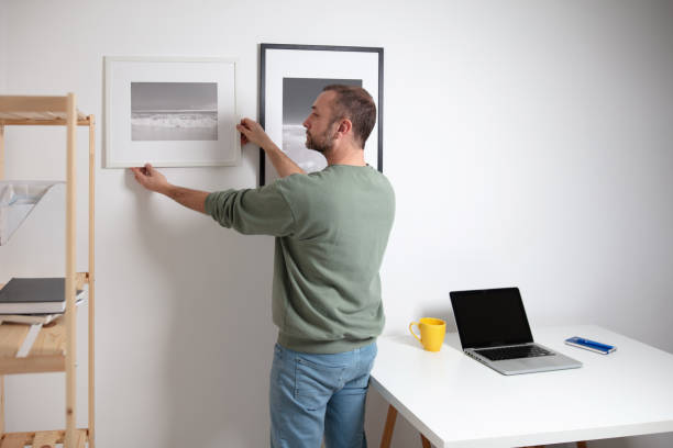 istock Man hanging pictures on the wall. 1980225357