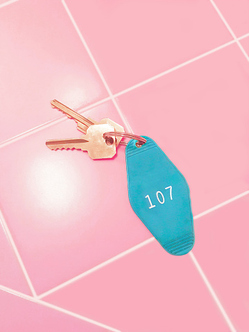 A set of motel or hotel room keys and a blue tag with 107 lying on a pink tile countertop.