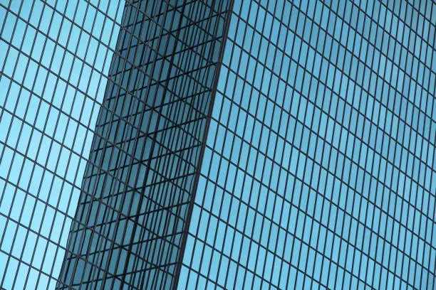 A high-rise building in the city with a blue glass grid and reflections.