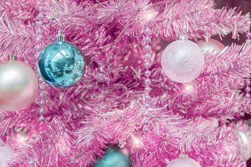 A close-up of a sparkling pink and silver tinsel Christmas tree with baubles and ornaments.