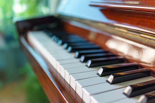 Old black grand piano keyboard with keys from ivory and ebony, part of a musical instrument in panoramic format, copy space, selected focus, narrow depth of field