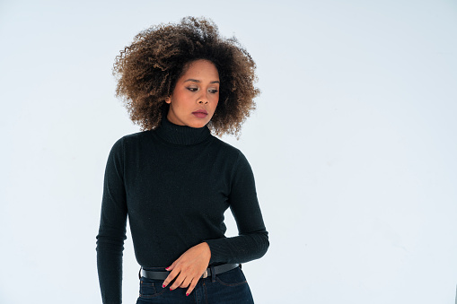 Latina woman of average age of 25 years dressed in black clothing with afro hair is inside a photographic studio where she is being photographed