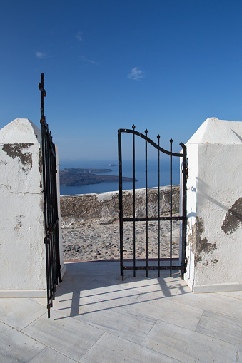 Santorini - The gate of church in Imerovigli with the look to Nea Kameni vulcanic island.