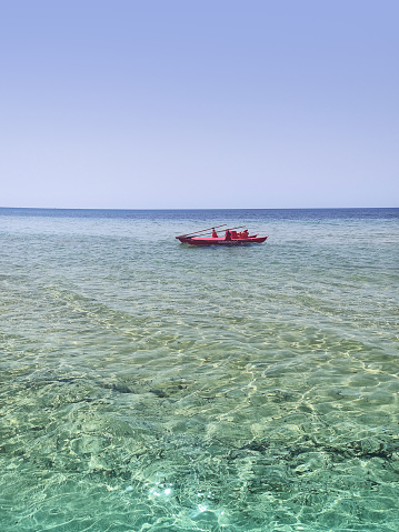 red rescue boat in the middle of the transparent and crystalline sea of ​​Sicily