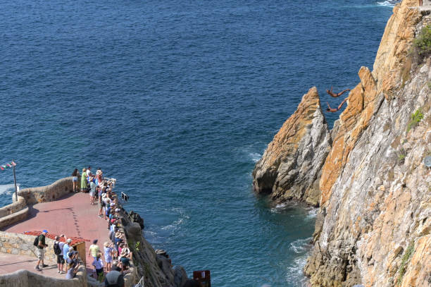Acapulco, Mexico - 17 January 2024: Tourists watch as the famous cliff divers dive into the sea at La Quebrada