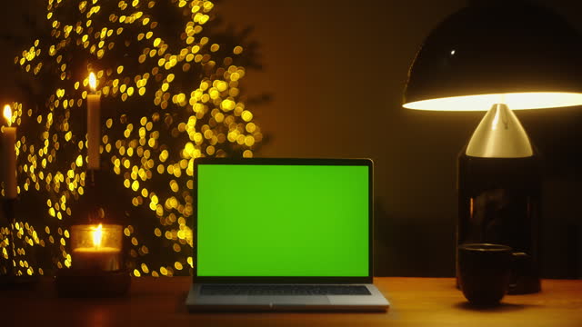 Experience the Magical Christmas Spirit with a Festive Desk Setup: Mock-up Chroma Key Green Screen and a Cozy Table Lamp Illuminating Your Workstation zoom 4k video template