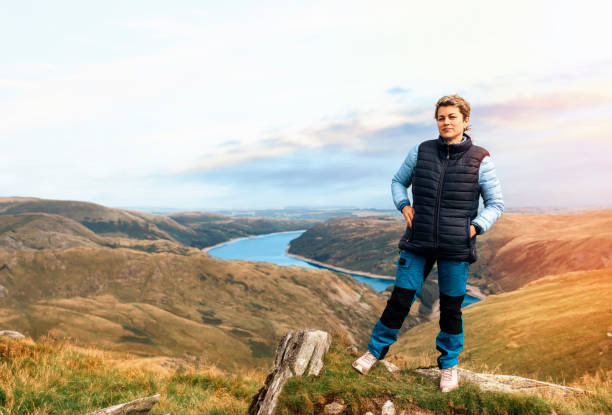 woman reaching the destination and on the top of mountain against cloudy blue sky on autumn day travel lifestyle concept the national park lake district in england - english lake district orienteering hiking mountain стоковые фото и изображения