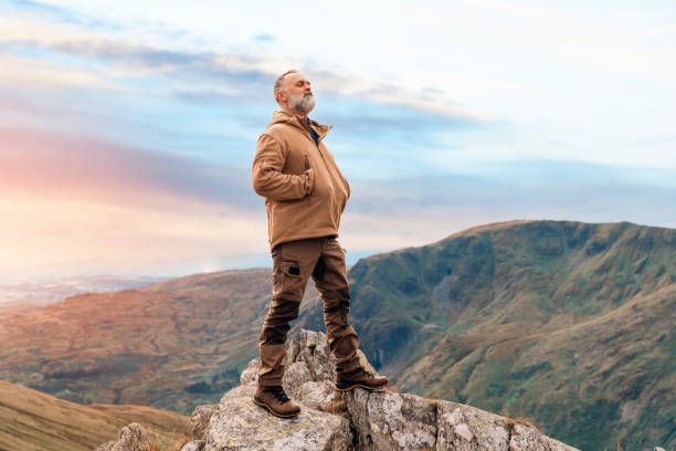 bearded man reaching the destination  and on the top of mountain  at sunset on autumn day  travel  lifestyle concept the national park lake district in england - english lake district orienteering hiking mountain стоковые фото и изображения