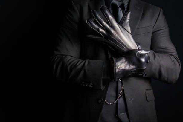 istock Man in Black Suit Pulling on Black Leather Gloves 1980308777