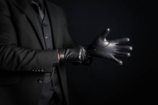 istock Man in Black Suit Pulling on Black Leather Gloves 1980308779