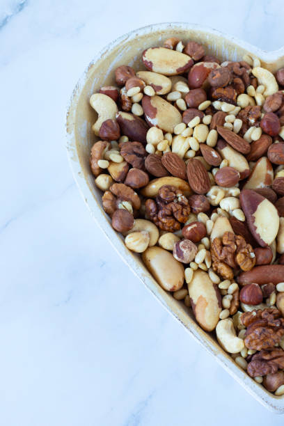 istock Mixed nuts (hazelnut, almond, walnut, Brazil, and pine nuts) in a heart-shaped dish isolated on white 1980308796