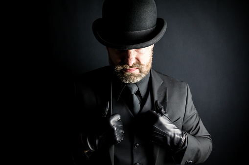 Portrait of Englishman in Dark Suit and Bowler Hat With a Mean Scowl. Concept of Gangster or Mafia Hitman.